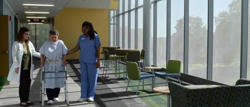 Image of two women offering support to a patient with a walker